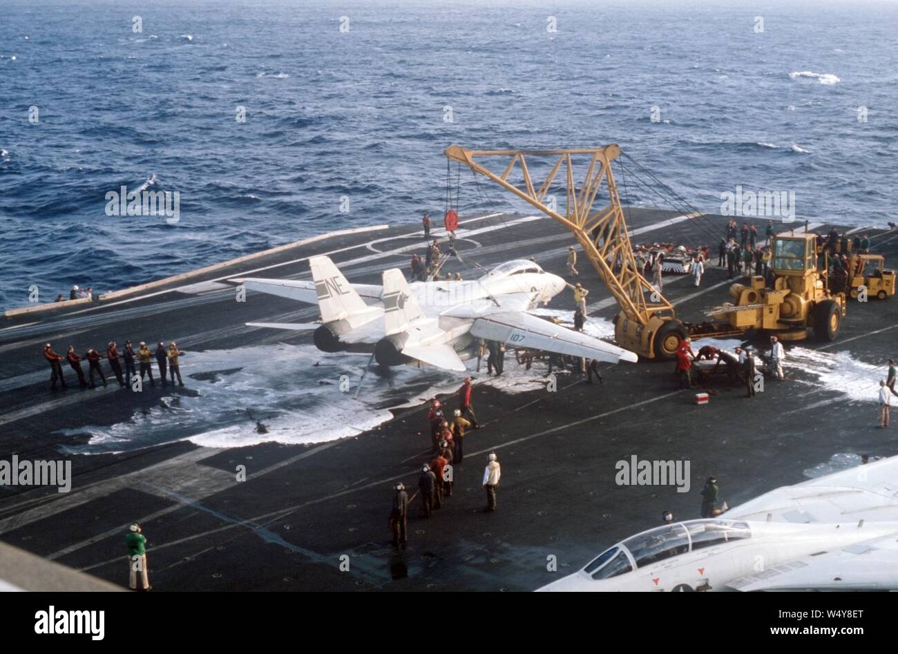 Gru solleva danneggiato F-14A di VF-1 sulla USS Kitty Hawk (CV-63) nel 1984. Foto Stock