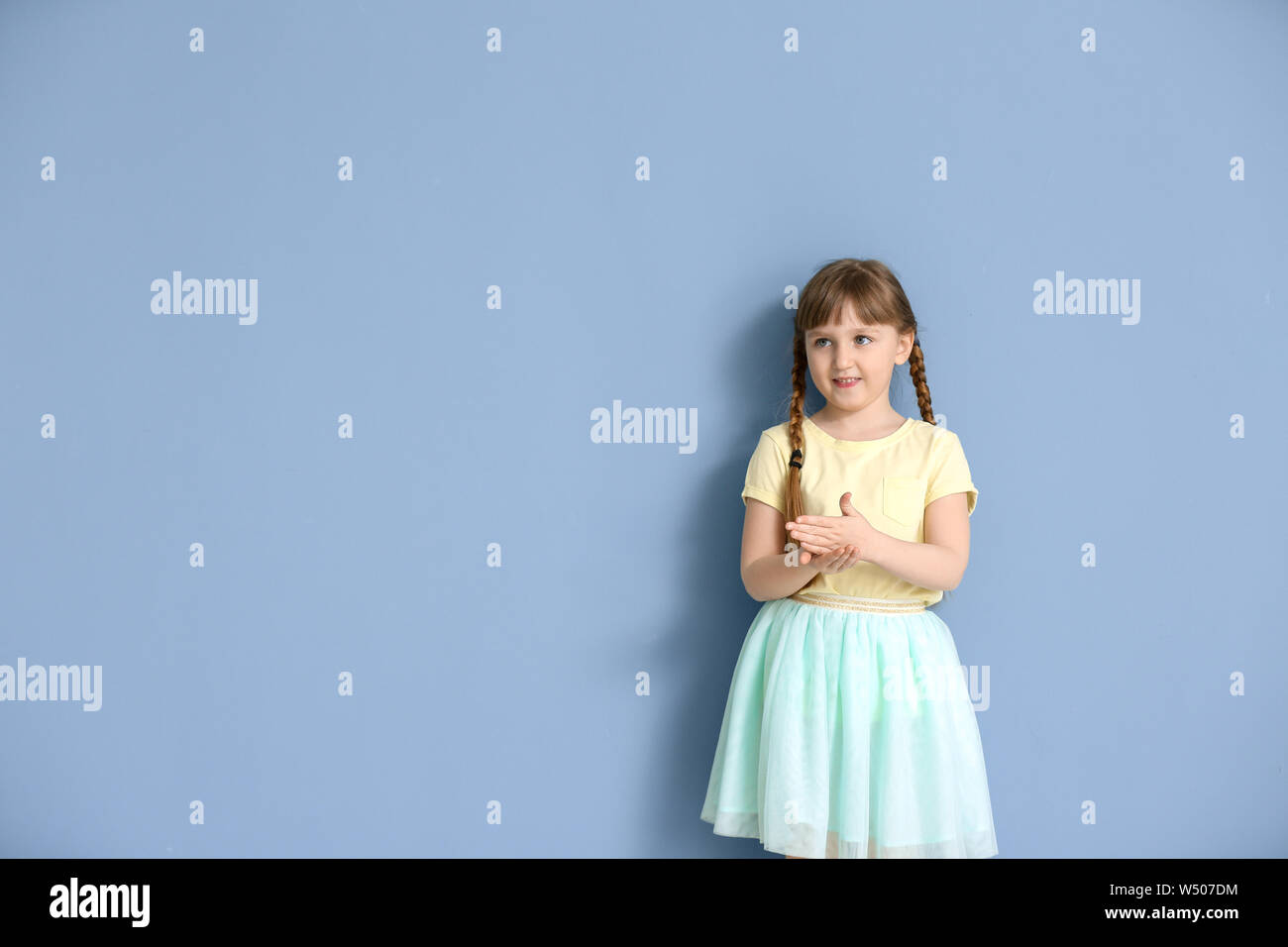 Carino sordomuto ragazza utilizzando il linguaggio dei segni sul colore di sfondo Foto Stock