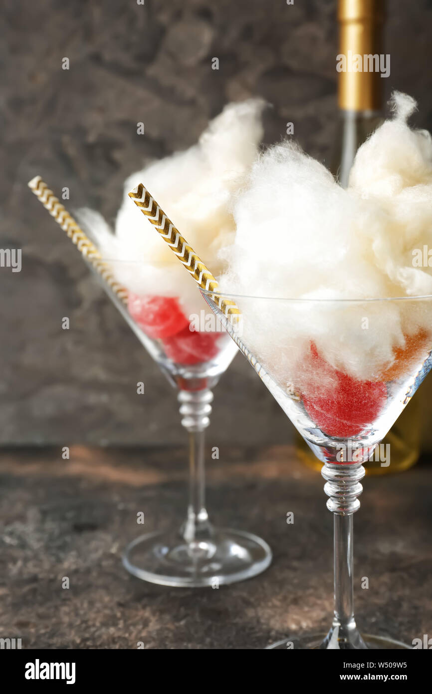 Gustosa caramella di cotone con dolci in bicchieri su sfondo grigio Foto Stock