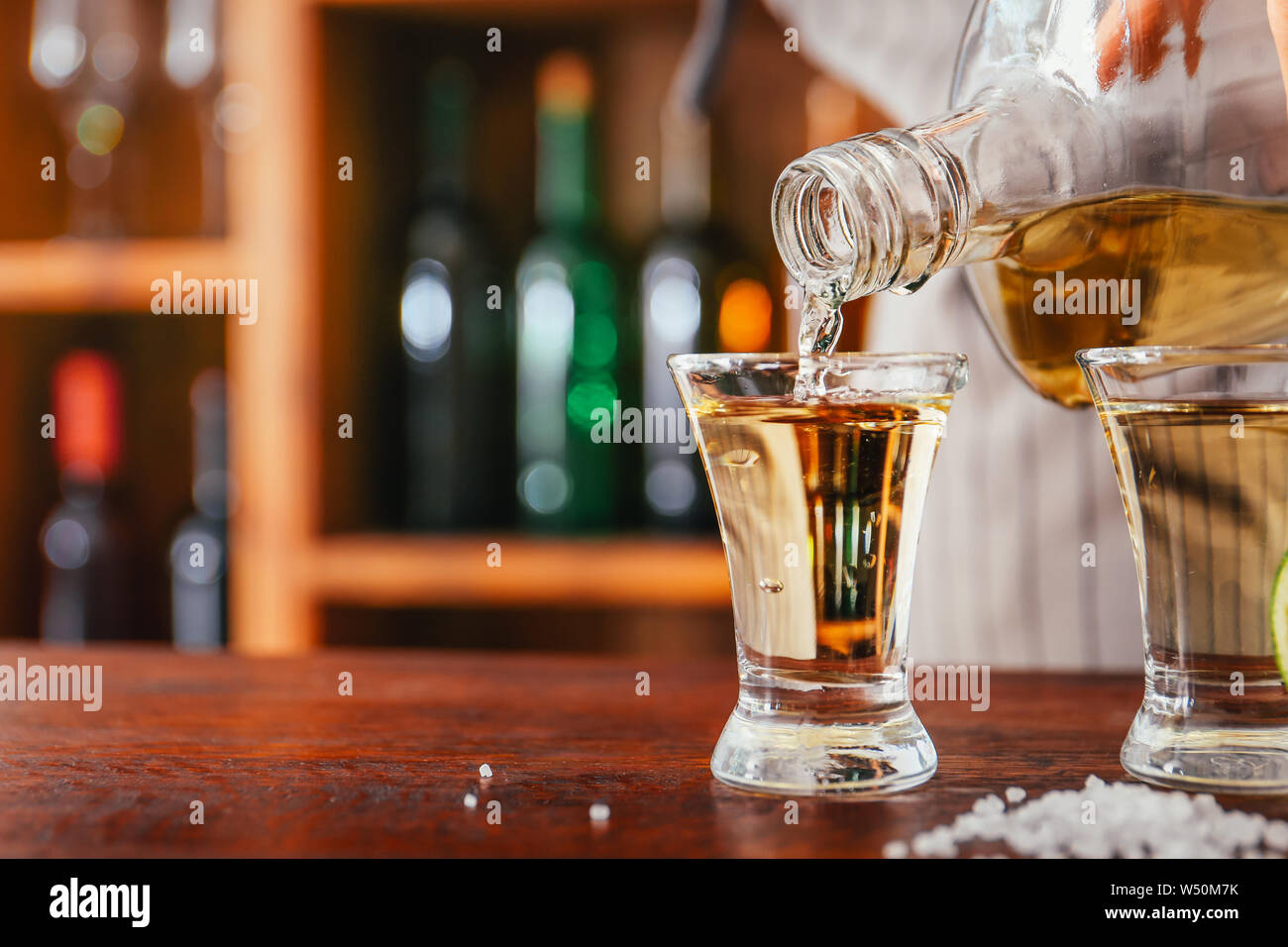 Barman versando una gustosa tequila dalla bottiglia in vetro sul contatore Foto Stock