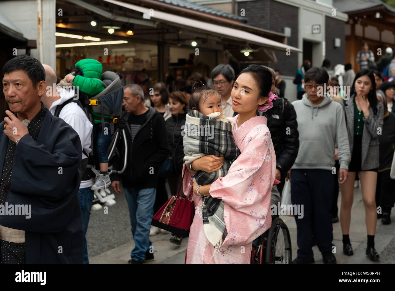 Kyoto, Giappone, Novembre 18, 2018: giovane donna in vestiti nazionali kimono tenendo un bambino in strada Foto Stock