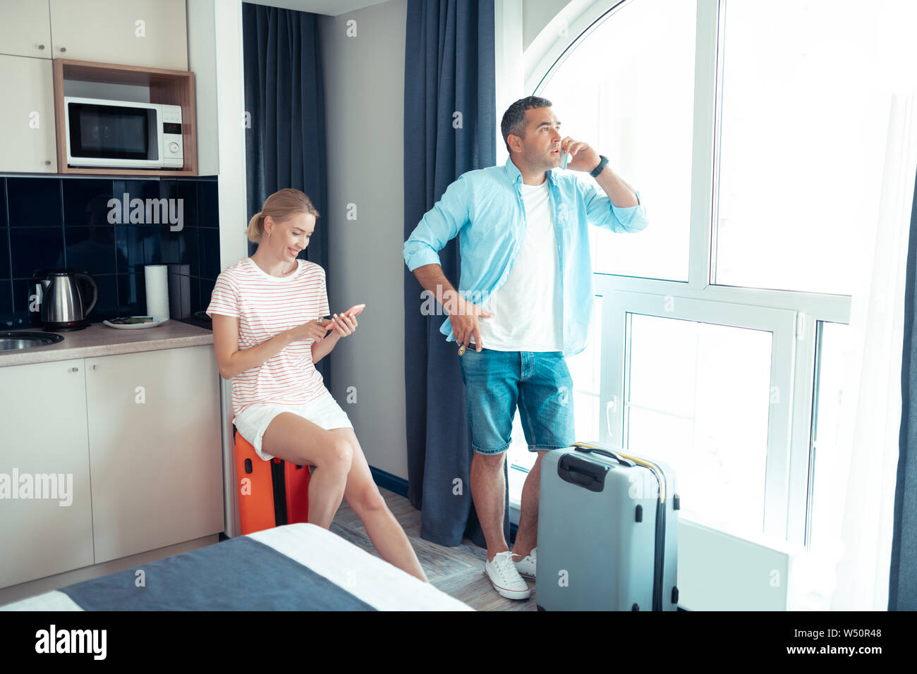 Andare in viaggio. Coppia di sposi pronti per andare in vacanza in cerca di un taxi per l'aeroporto seduti sulle loro pranzo travelware. Foto Stock