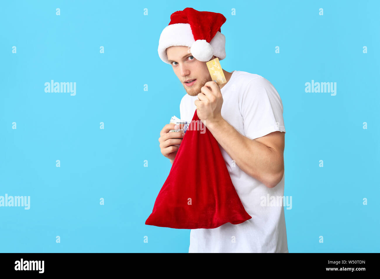 Diffidenti giovane Santa hat, con carta di credito, il denaro e la borsa sul colore di sfondo Foto Stock