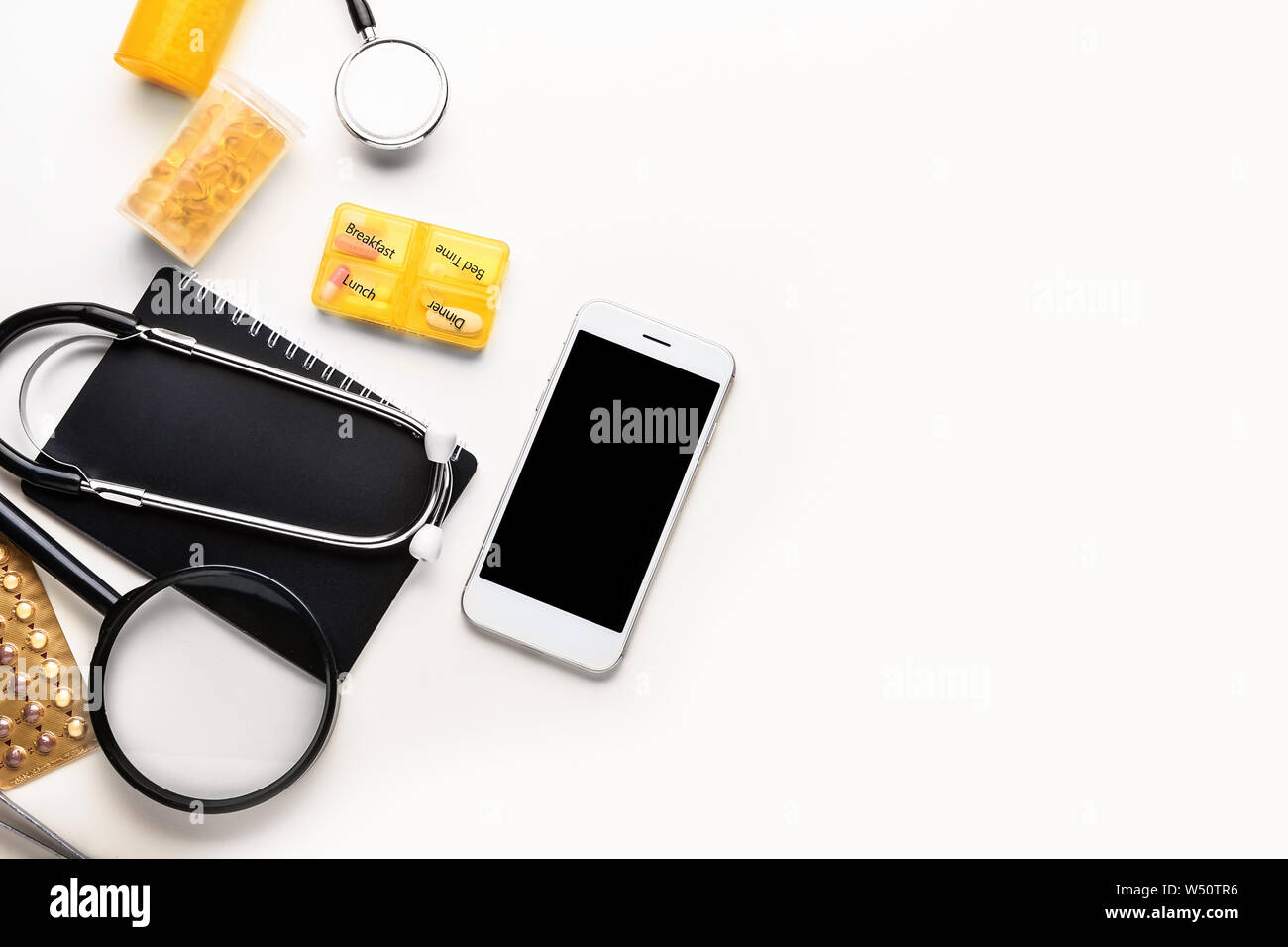 Luogo di lavoro del medico con il cellulare su sfondo bianco Foto Stock