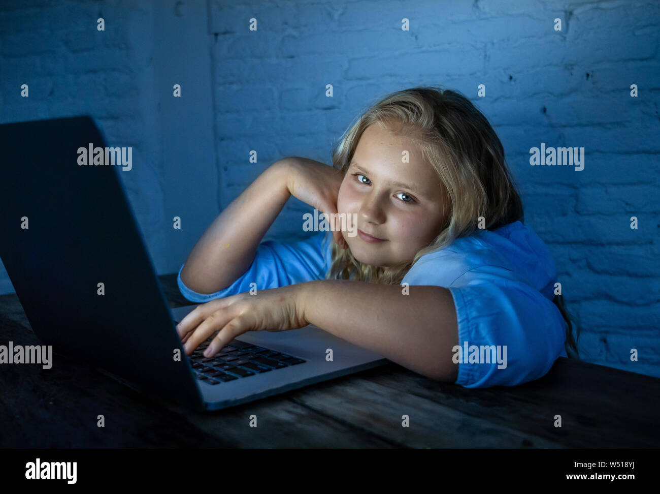 Carino schoolgirl bambino la riproduzione e la navigazione online a tarda notte. Bambino addicted ai giochi su internet e i social media non riesce a dormire agganciata sul laptop. Digita Foto Stock