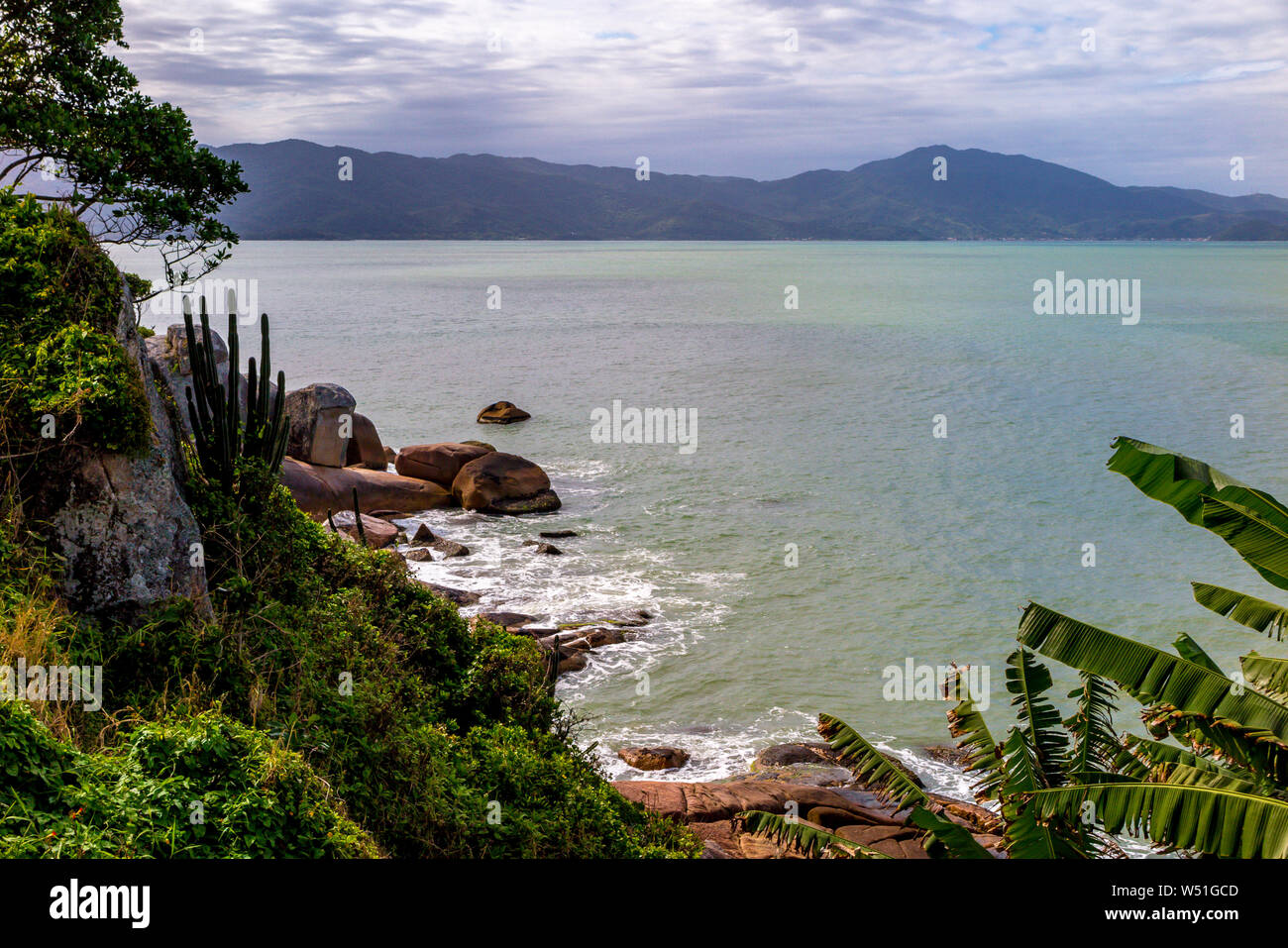 Vista del mare, dalla Fortezza di Sao Jose da Ponta Grossa, con rocce, alberi e montagne sullo sfondo Foto Stock
