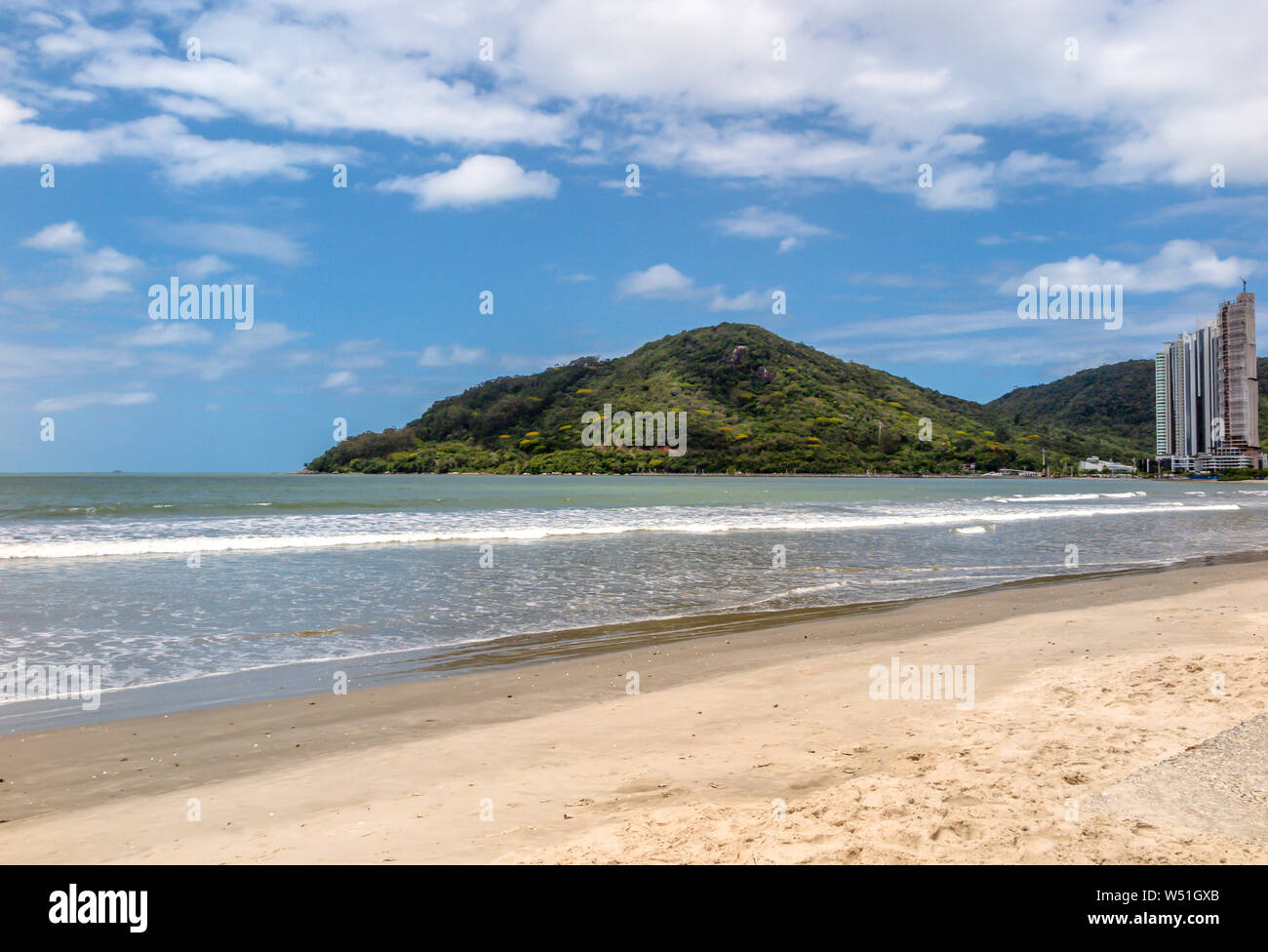 Vista dal lato destro del Balneário Camboriú spiaggia centrale con una collina in background e cielo blu con nuvole Foto Stock