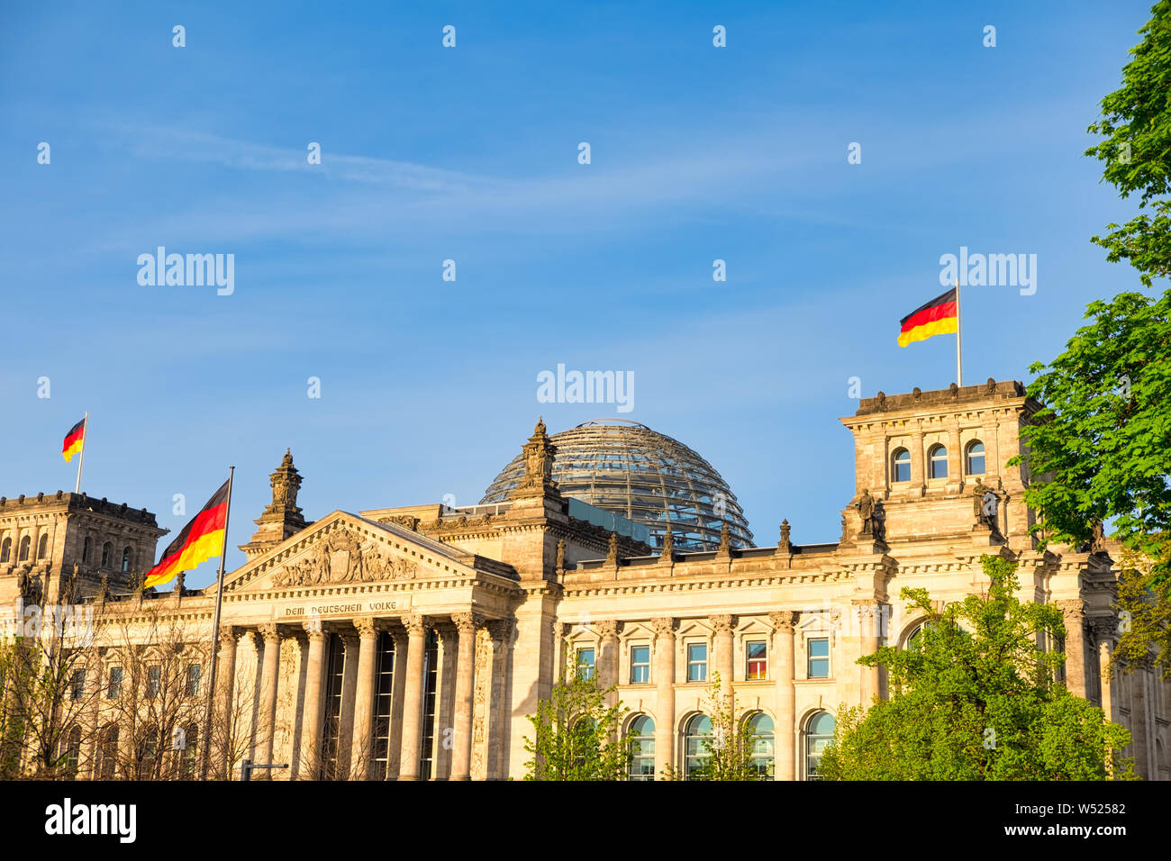 L'edificio del Reichstag di Berlino in Germania con la bandiera tedesca. Un famoso punto di riferimento e meta di viaggio per i turisti Foto Stock