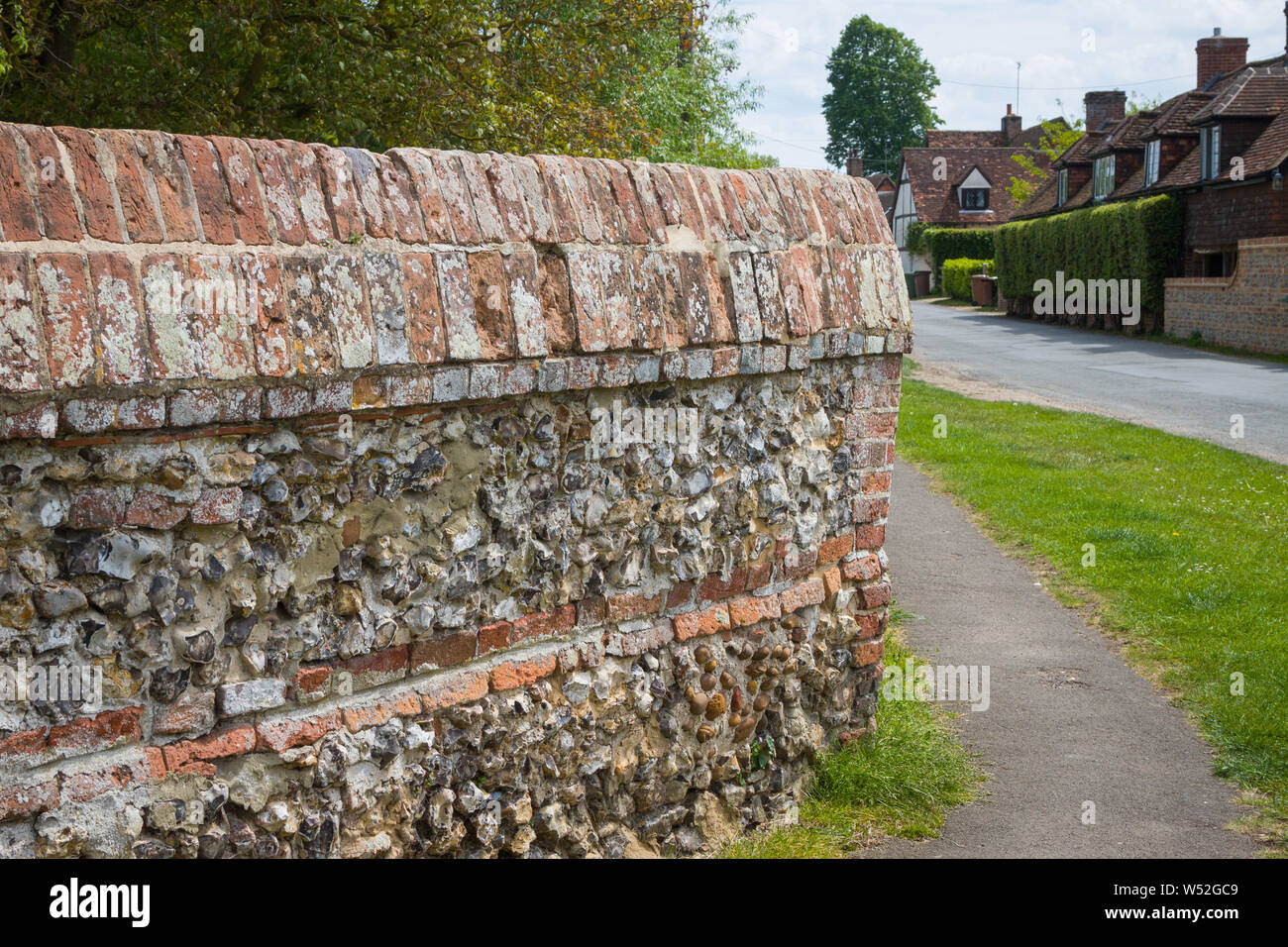 Un tradizionale in mattoni e pietra focaia parete con coperture decorative nel villaggio di South Stoke, Oxfordshire Foto Stock