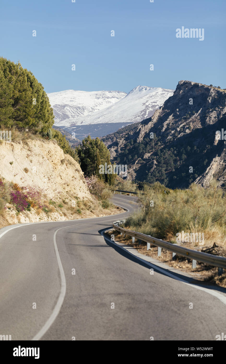 La strada attraverso la Spagna Sierra Nevada in Andalusia con una montagna innevata in background Foto Stock