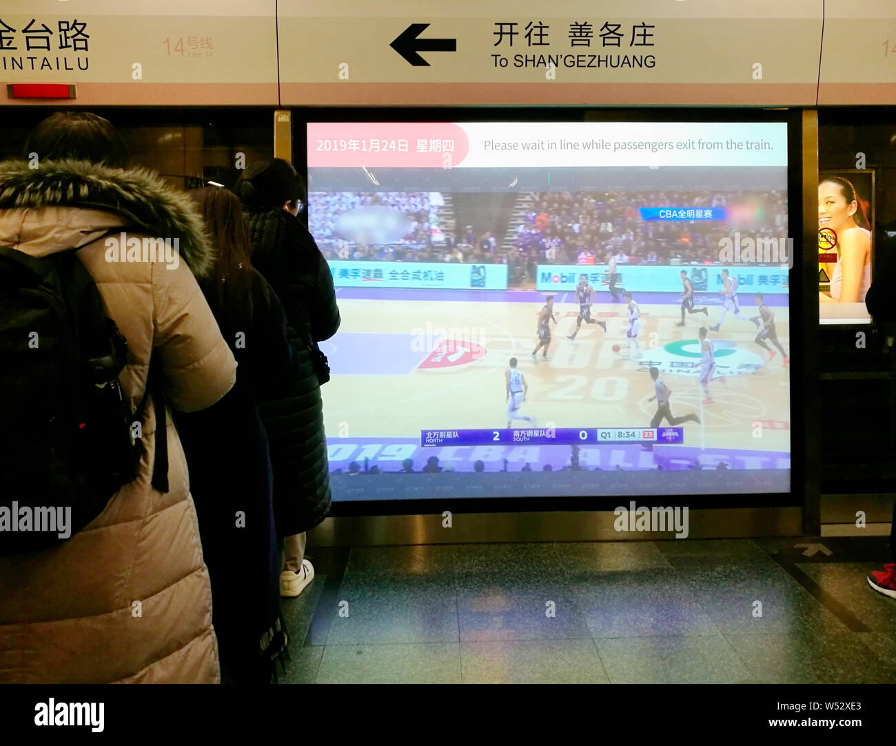 Pedoni guardare la proiezione media su una piattaforma porta dello schermo come sono in attesa di un treno della metropolitana presso la stazione di Jingtai sulla linea 14 di Pechino su Foto Stock
