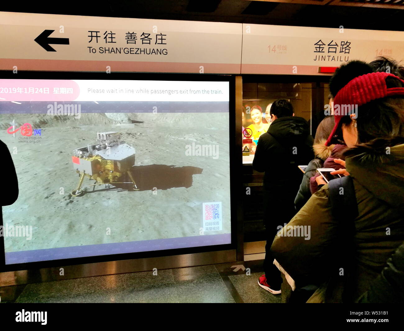 Pedoni guardare la proiezione media su una piattaforma porta dello schermo come sono in attesa di un treno della metropolitana presso la stazione di Jingtai sulla linea 14 di Pechino su Foto Stock