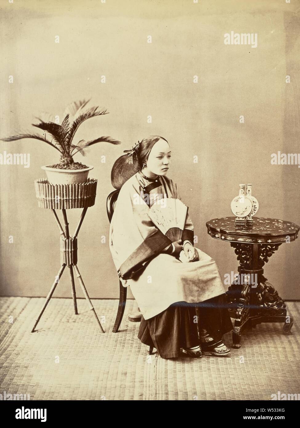 Studio ritratto di una giovane seduto signora cinese tenendo un ventilatore, William Saunders (inglese, 1832 - 1892), Cina, 1860-1880, albume silver stampa, 27,5 × 20,5 cm (10 13/16 × 8 1/16 in Foto Stock