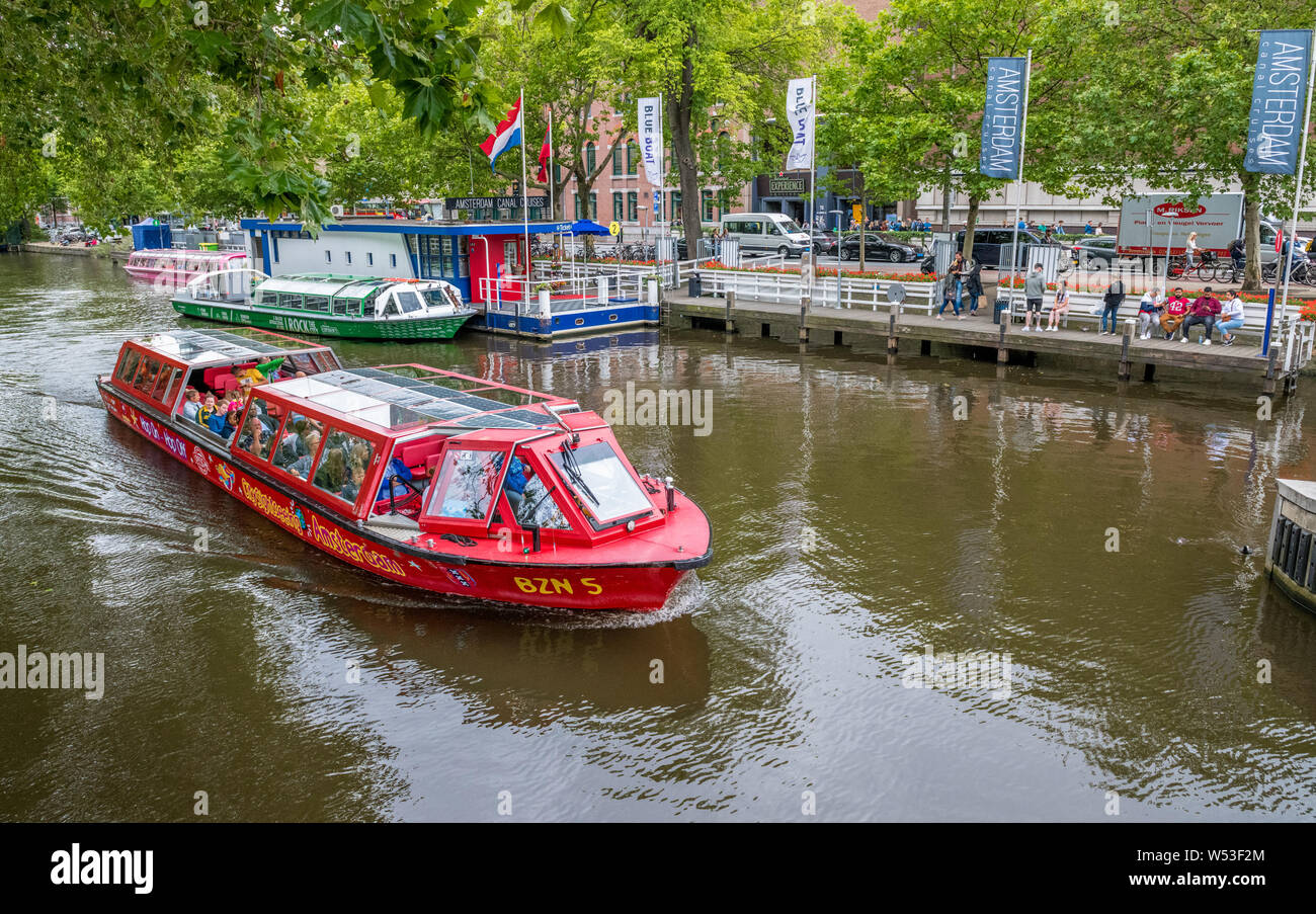 I turisti prendendo un canal gita in barca sui molti canali intorno la città olandese di Amsterdam. Foto Stock