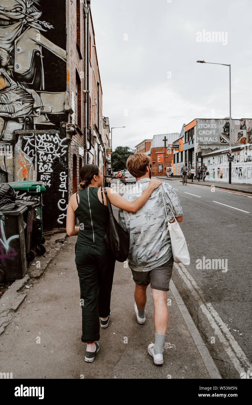 Una giovane coppia composta da una donna e uomo a camminare per la strada a Bristol. Foto Stock