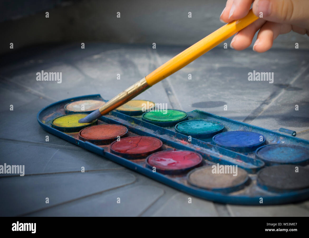 Un close-up di una ragazza di disegno con colori di acqua sulla luce naturale Foto Stock