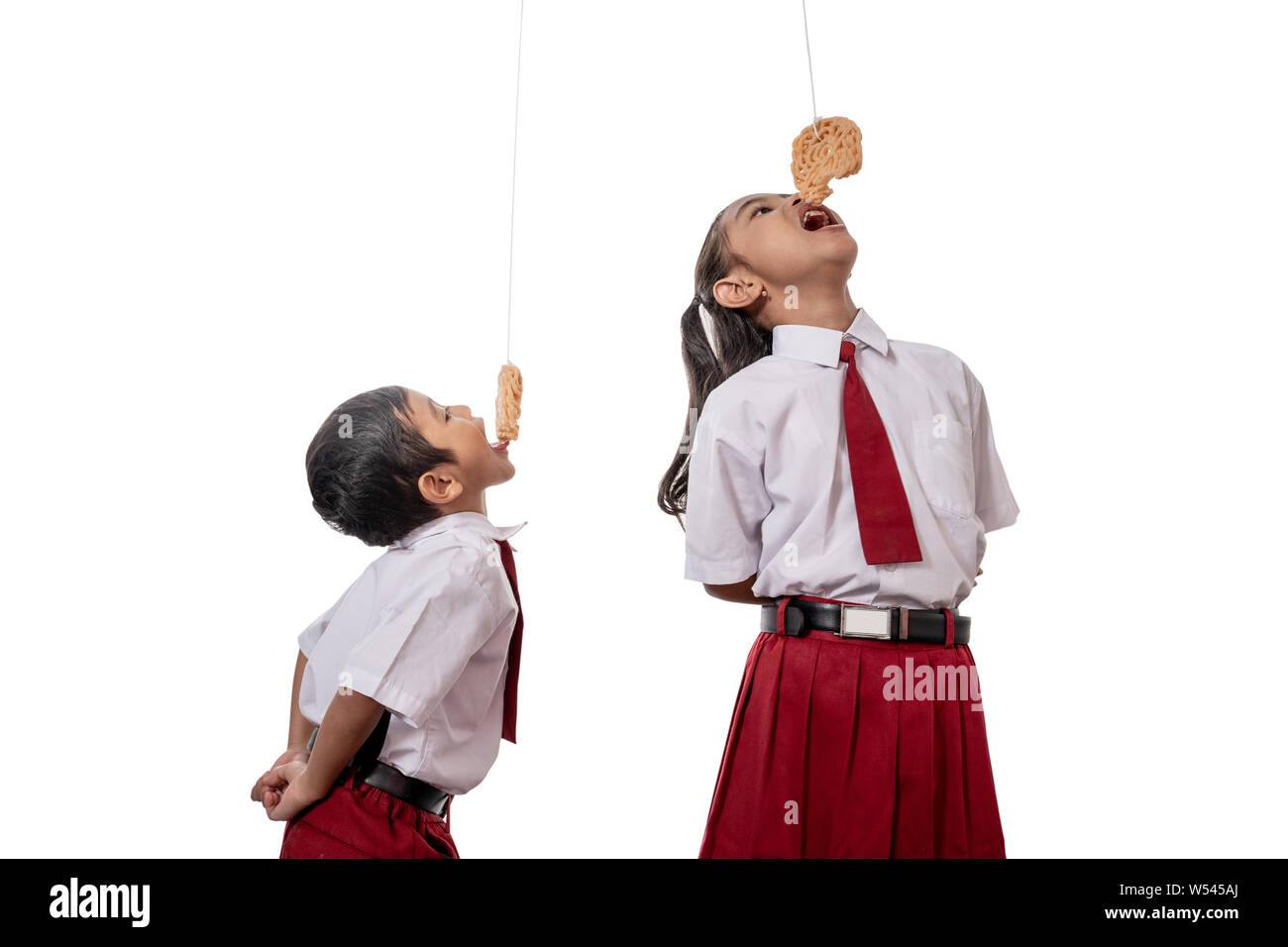 Bambini contro ogni altro mangiare cracker indonesiano il giorno dell'indipendenza Foto Stock