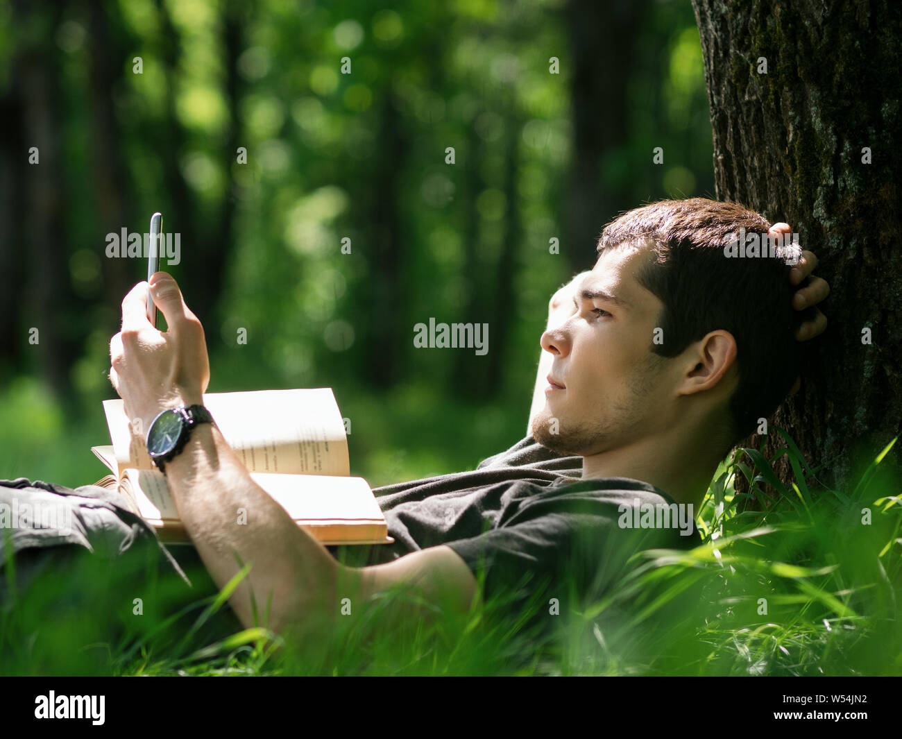 Giovane uomo caucasico o studente la lettura di un libro nel parco. Orario estivo e attività ricreative all'aperto Foto Stock