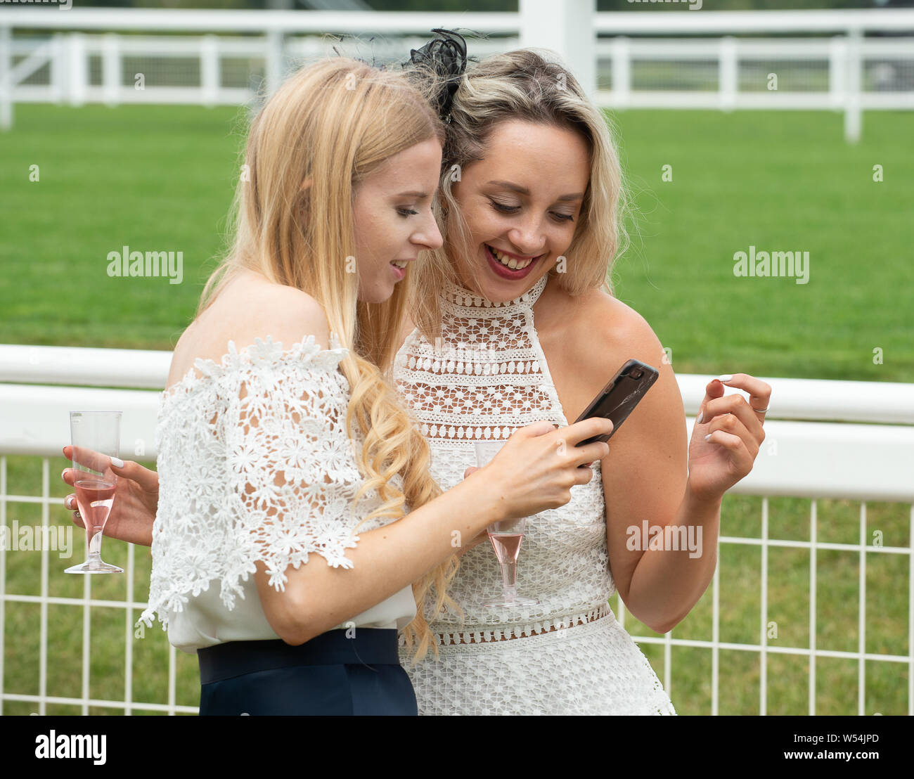 Ascot Racecourse, Ascot, Regno Unito. 26 Luglio, 2019. Controllo fuori il loro telefono mobile per la foto di due giovani ragazze a Ascot Racecourse. Credito: Maureen McLean/Alamy Live News Foto Stock