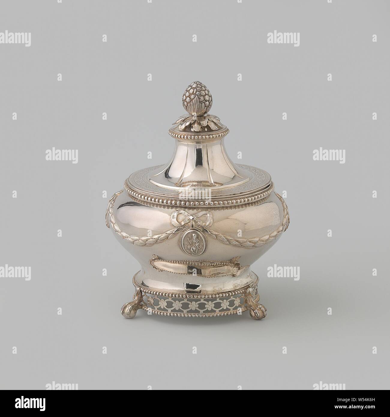 Vaso di tabacco, rotondo, decorata con imposte ghirlande e medaglioni con coperchio allentato, la rotonda di tabacco jar ha un coperchio allentato e poggia su tre gambe colati in forma di un uccello's claw su una sfera. Le gambe sono attaccate a un open-bordo lavorato di ovali collegate lungo la parte inferiore del corpo collegati da rosette, chiuso superiormente ed inferiormente da un bordo a perline. Il corpo è leggermente ristretta da sotto e il soffitto a volta al di sopra di esso. Essa ha un basso dritto il bordo di bocca decorato con un telaio di perla. Esso è guidato intorno con un pendolo di alloro, che è attaccata ad un anello su entrambi i lati dove un pendolo diritta Foto Stock