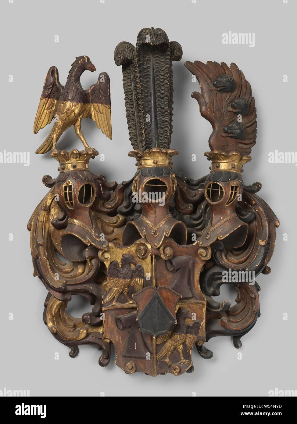 Stemma di legno scolpito in legno stemma, parzialmente dorato e ulteriormente verniciati in nero, rosso-marrone e viola. Lo stemma è squartato e mostra un aquila in due campi e una cappa in due campi. Lo schermo ha anche imposto un cuore scudo. Dell'Arma sono tre elmo coronato con segni di un'aquila, tre piume di struzzo e un'ala, in cui tre cinghiali capi. Il tutto è circondato da foglie simmetriche lavoro., anonimo, Zuid-Duitsland, c. 1500 - c. 1600, di legno (materiale vegetale), doratura (materiale), doratura, h 110 cm × W 78 cm × d 18 cm × W 17 kg Foto Stock