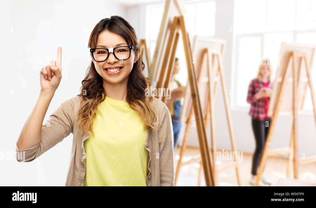 Donna asiatica in bicchieri o studente con il dito verso l'alto Foto Stock