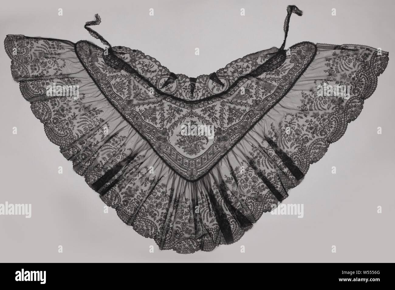 Capo di nero merletto a fuselli con bouquet sul retro, Capo di nero il merletto a tombolo: pizzo Chantilly. Il capo ha premuto una forma triangolare con le punte arrotondate, con in fondo una larga striscia che è stropicciata e nella parte superiore una stretta striscia che è stata prevista con la forma corretta con alcune grandi figura cuciture. Al centro della schiena è un bouquet di grandi dimensioni nel centro di uno schema simmetrico con fiori separato con sfere a zig-zag ghirlanda di foglie in tra. L'ampia fascia pieghettata lungo la parte inferiore ha un bordo di guscio che è composta da grandi c-volute che, quando si è allontanata da ogni altro Foto Stock