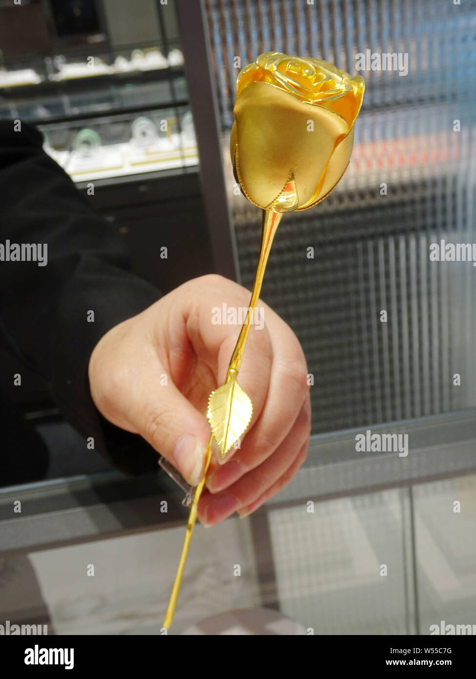 Un dipendente cinese mostra una rosa d oro per la vendita in un negozio gioielli nella città di Shaoxing, est della Cina di provincia dello Zhejiang, 14 febbraio 2019. Le rose fatte di Foto Stock