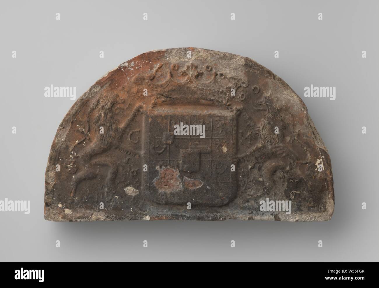 Camino capstone con lo stemma del principe Maurits di Orange Nassau, heartstone semicircolare con stemma del principe Maurits, sopra la protezione corona e .6., su entrambi i lati i Lions - sinistro con la lettera G tra gambe anteriori di destra con m tra le gambe anteriori - e motivi vegetali, semplice bordo in rilievo, molto usurato e bordo pezzi, protezione, molto usurati, annerito, cemento rimane, scala bianco lato sinistro con linea tratteggiata, vernice bianca schizza, Maurits (principe di Orange), anonimo, Paesi Bassi, 1567 - 1625, terraglia, h 20 cm × W 33 cm × d 6,2 cm Foto Stock