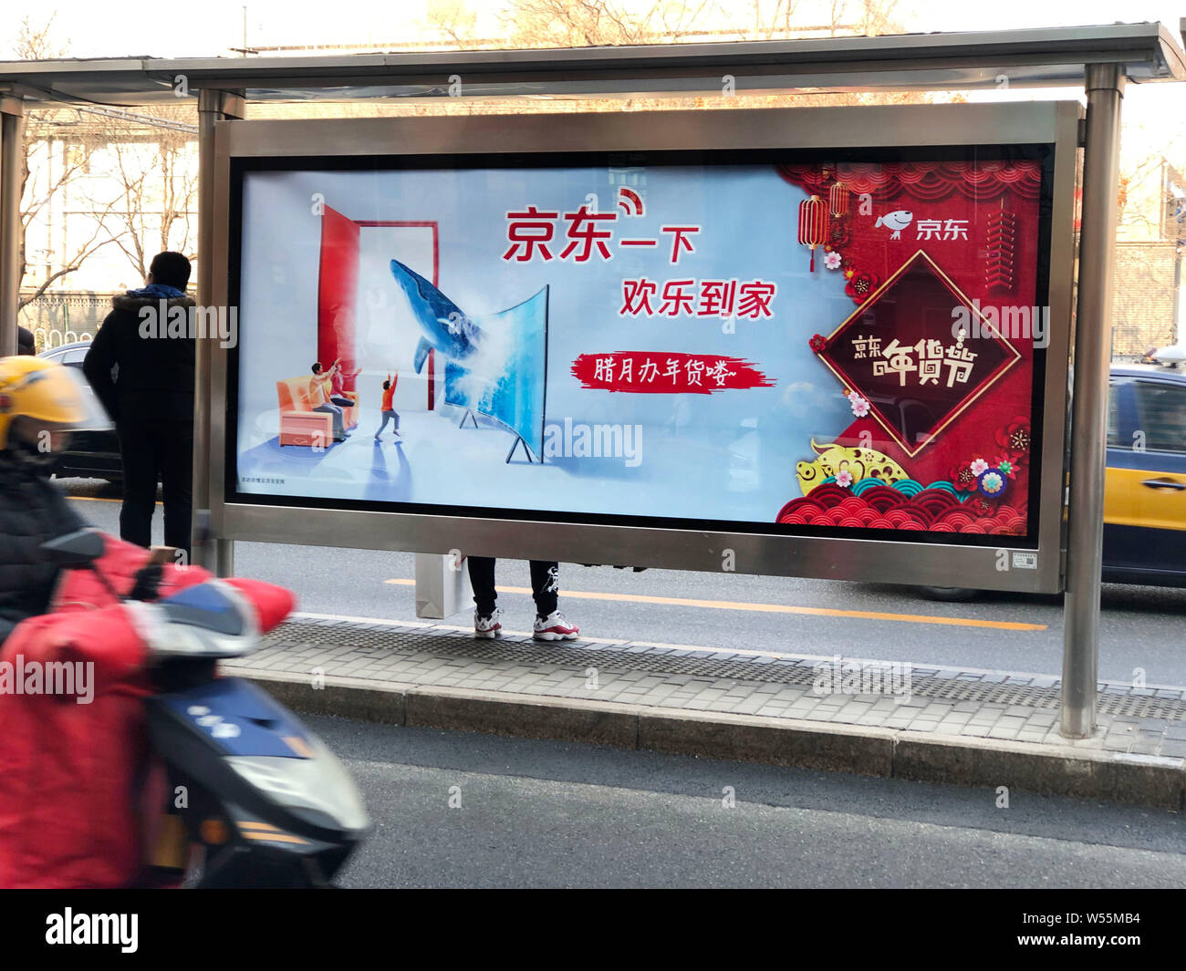 --FILE--un ciclista passa su un annuncio pubblicitario per il cinese e-commerce JD.com gigante su una fermata di autobus di Pechino, Cina, 24 gennaio 2019. Il cinese e-commer Foto Stock