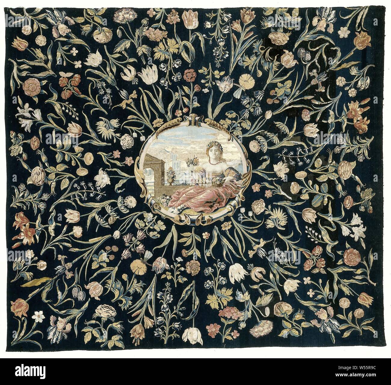 Tovaglia con la personificazione della flora e un pattern di fiori, tovaglie realizzata in tessuto tappezzeria con la flora in mezzo all'interno di un cartiglio e fiori sparsi intorno ad esso su uno sfondo blu scuro., Maximiliaan van der Gucht (eventualmente), il nord dei Paesi Bassi, c. 1650 - c. 1675, ketting, inslag, arazzi, h 194.0 cm × w 218.0 cm Foto Stock