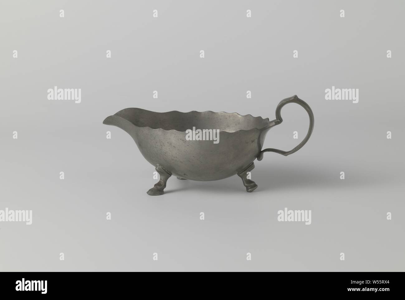 Ciotola di salsa con bordo dentellato, Salsa ciotola di stagno su quattro gambe. Il vaso termina da un lato in un tubo di lancio. L'altro lato è scanalata. Vi il manico è acceso. Il bordo della tazza è dentellata., anonimo, Nederlanden, c. 1700 - c. 1800, stagno (metallo), l 21,0 cm × W 10,0 cm × h 10.0 cm Foto Stock