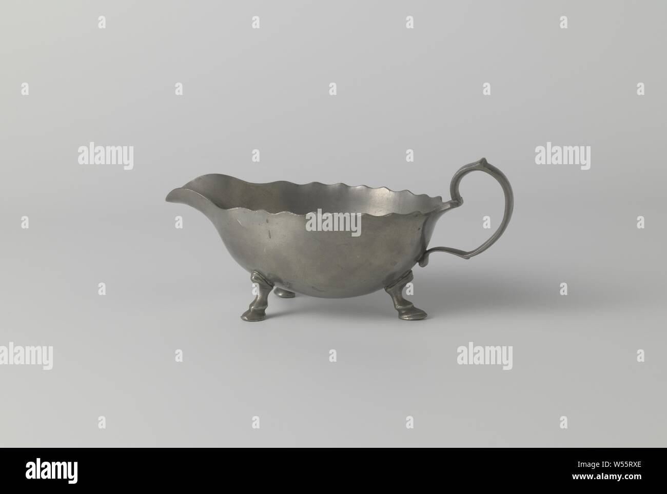 Ciotola di salsa con bordo dentellato, Salsa ciotola fatta di stagno su quattro zampe. Il vaso termina da un lato in un tubo di lancio. L'altro lato è scanalata. Vi il manico è acceso. Il bordo della tazza è dentellata., anonimo, Nederlanden, c. 1700 - c. 1800, stagno (metallo), l 21,0 cm × W 10,0 cm × h 10.0 cm Foto Stock