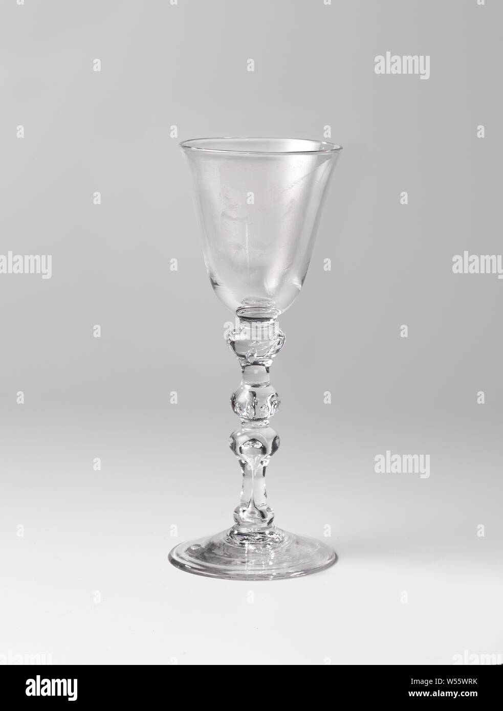 Calice con due putti sulle nuvole, piede arcuato. Balaustra con stelo a forma di goccia di bolle di aria, due nodi con un anello di bolle di aria. Calice conico arrotondato in corrispondenza del fondo. Due putti sul calice, la sinistra della quale solleva il vetro. Al di sopra della mostra un banderolle con il testo: L'amicizia., anonimo, c. 1760 - c. 1780, vetro, glassblowing, h 19.5 cm × d 8 cm Foto Stock