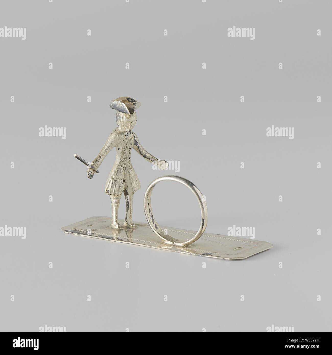 Cerchiatura boy, sta un uomo dietro un cerchio su una piastra allungata. Il ragazzo porta un punto ed ha un bastone nella sua mano destra. La piastra è incisa una linea a zig-zag lungo il bordo. L'immagine viene contrassegnata con una spada e un master mark, (bowling a) speranza, W. Freen, Dordrecht, c. 1856 - c. 1858, argento (metallo), l 7,6 cm × h 3.6 cm × W 2.1 cm × w 15.00 Foto Stock