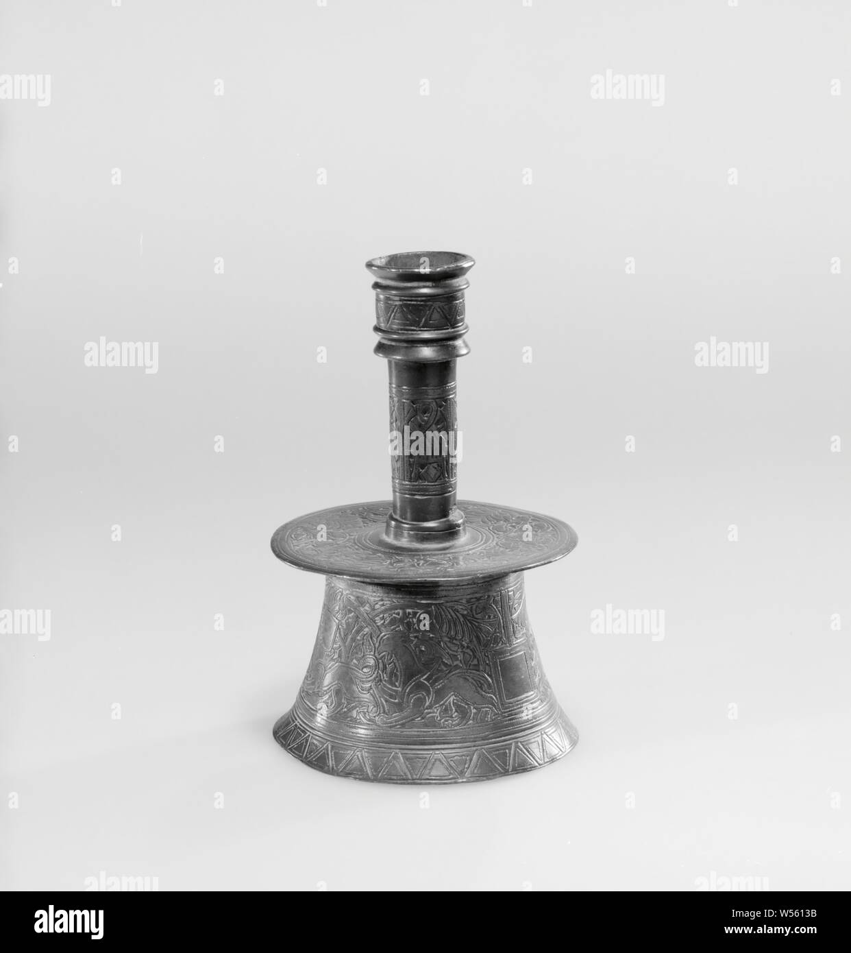 Candelabro con intagliato e scolpito ornamento, comprendente un mantello vuoto di bracci, viticci e animali. Lo scopo consiste di tre parti: la base su cui la trappola del grasso è goffrato e il tronco cavo, che è anche un candelabro e collocato sul grasso trappola è rivettata. Essi includono un intagliato e scolpito ornamento, alcune parti del quale sono stati probabilmente intarsiato con argento, come forse si vede dalle linee tratteggiate entro i contorni di questi dettagli. Il piede ha un confine diviso in triangoli e un fregio costituito da un mantello bianco di bracci e simmetrica dei sarmenti ornamento, ciascuno dei quali include Foto Stock