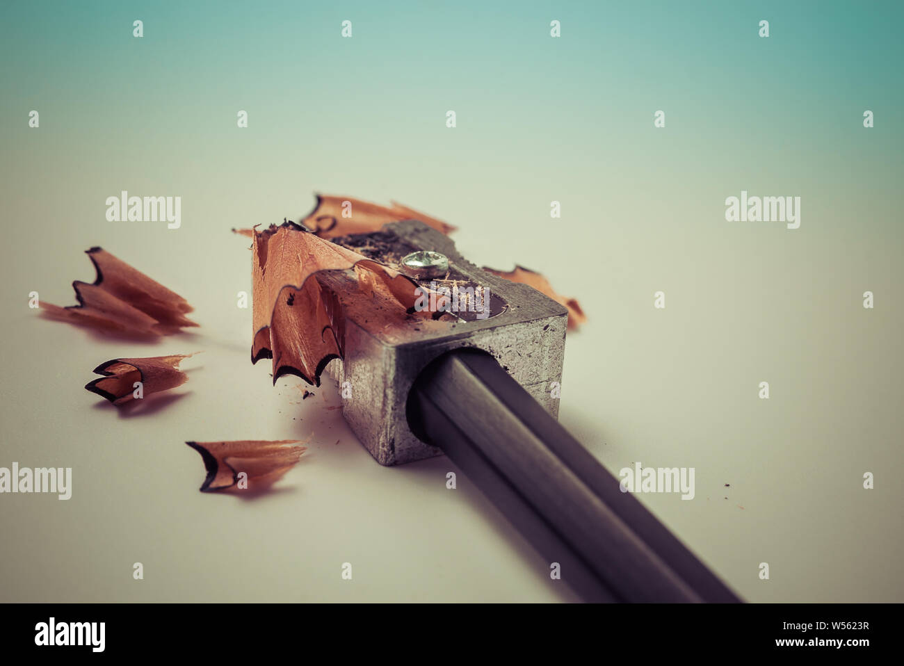 Primo piano di affilatura di una matita con un metallo grigio temperamatite con trucioli di legno - Concetto di istruzione scolastica, apprendimento, studente Foto Stock