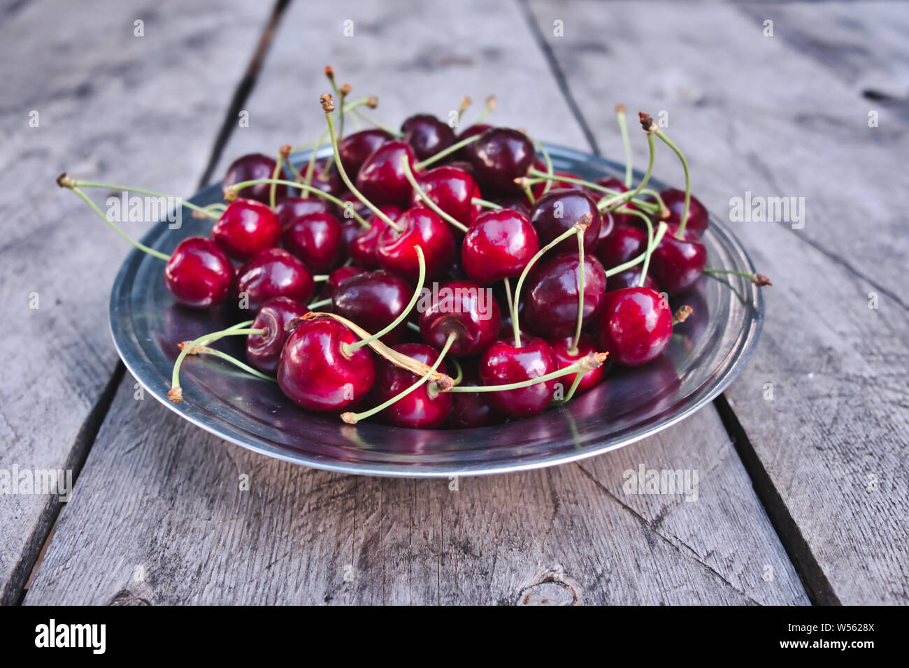 La ciliegia, rosso ciliegie mature nella piastra e sul tavolo di legno Foto Stock