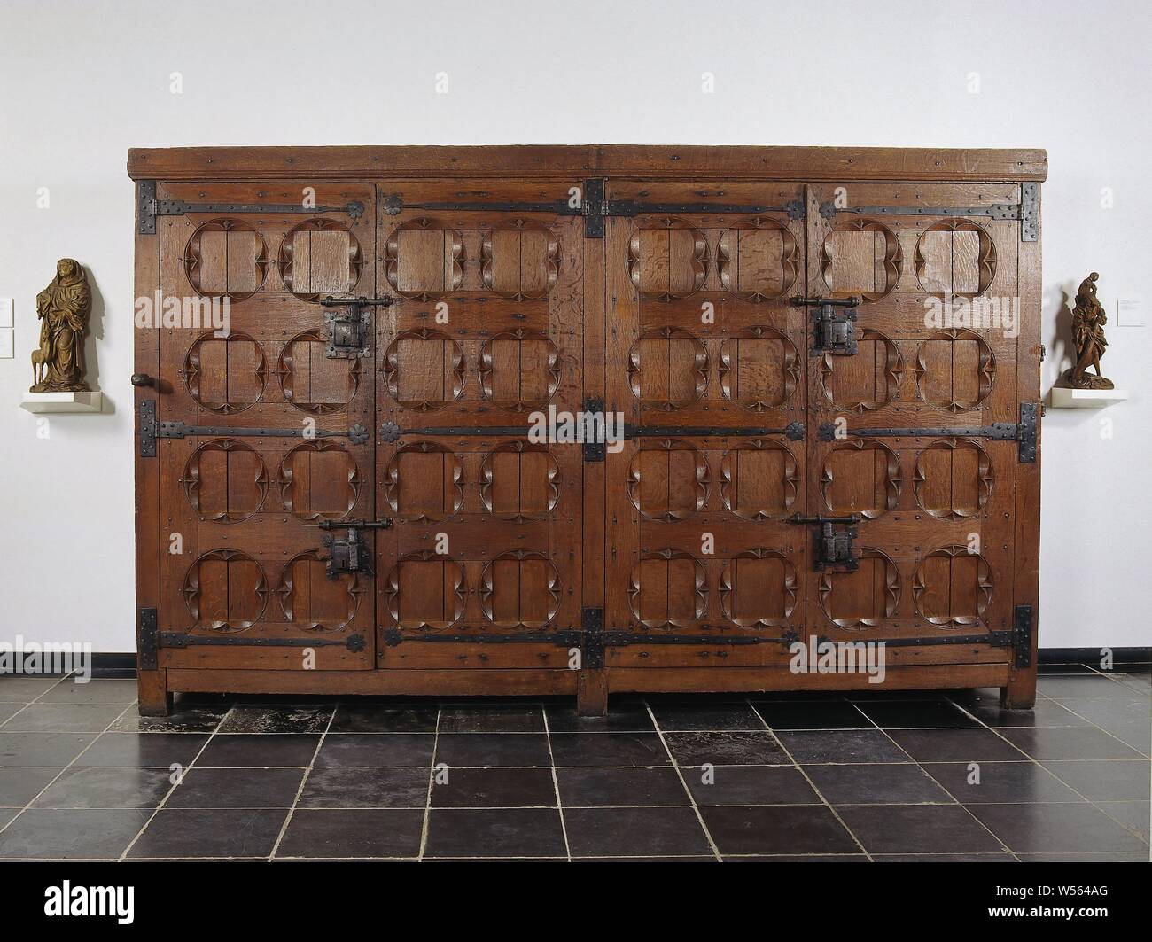 Filing cabinet in Utrecht, armadio archivio in legno di rovere. Due continuo di posti di angolo e un medio post trasportare quattro porte sollevata sulla croce di ferro maniglie. I quadrati ottenuti dall'intersezione di ganci sono espressi in ambienti in stile gotico. Ciascuna coppia di porte ha due serrature di ferro con le viti. Un rubinetto con un foro è attaccato ad un angolo di post e una staffa girevole sull'altro. All'interno di quaranta dei cassetti originale con il gotico majuskels. Dal Dom Capitolo a Utrecht, Utrecht, anonimo, Paesi Bassi del Nord, 1500 - 1550, il legno (materiale vegetale), Rovere (legno), ferro (metallo), h 221.0 cm × w 354.0 cm × d 91,0 cm w 351.0 cm Foto Stock