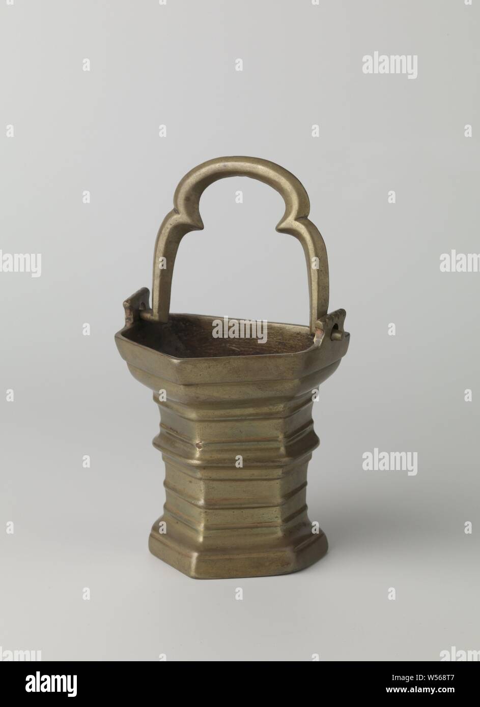 L'acqua santa benna, cinque facciate, l'oggetto è composta delle parti seguenti: il cucchiaio con le estensioni (cast), la maniglia (cast). Il bordo superiore di allegati è dentellata mediante goffratura. Quattro lati della benna hanno un profilo derivato dall'architettura, il quinto è liscia e forma la parte posteriore. La benna si protende verso il bordo di sommità e al piede cavo. Il piano orizzontale il bordo ha un attacco rettangolare su entrambi i lati con un occhio di riguardo per la maniglia. Questo è progettato come un treppiede e in sezione trasversale meno la forma di un esagono piana., anonimo, Paesi Bassi meridionali, c. 1475 - C Foto Stock