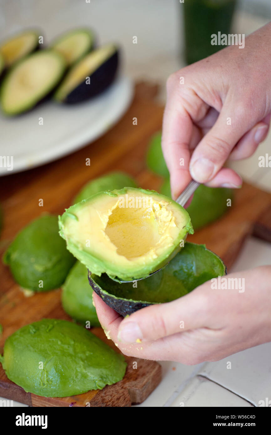 Materie vegano dieta alimentare. Bella di avocado maturo che viene rimosso dalla pelle. Foto Stock