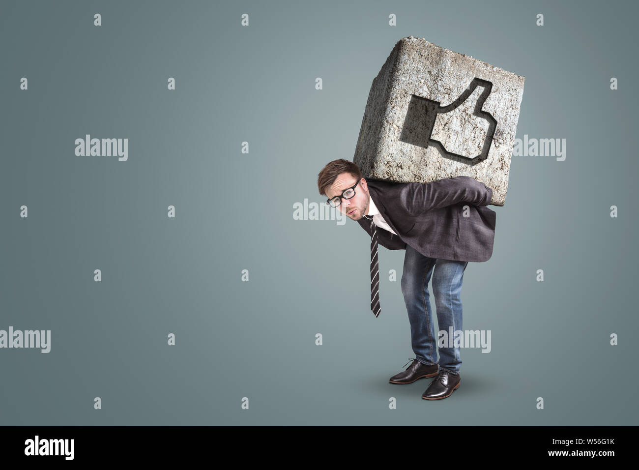 L'uomo flessione sotto un massiccio di pietra con un pulsante simile su di esso Foto Stock