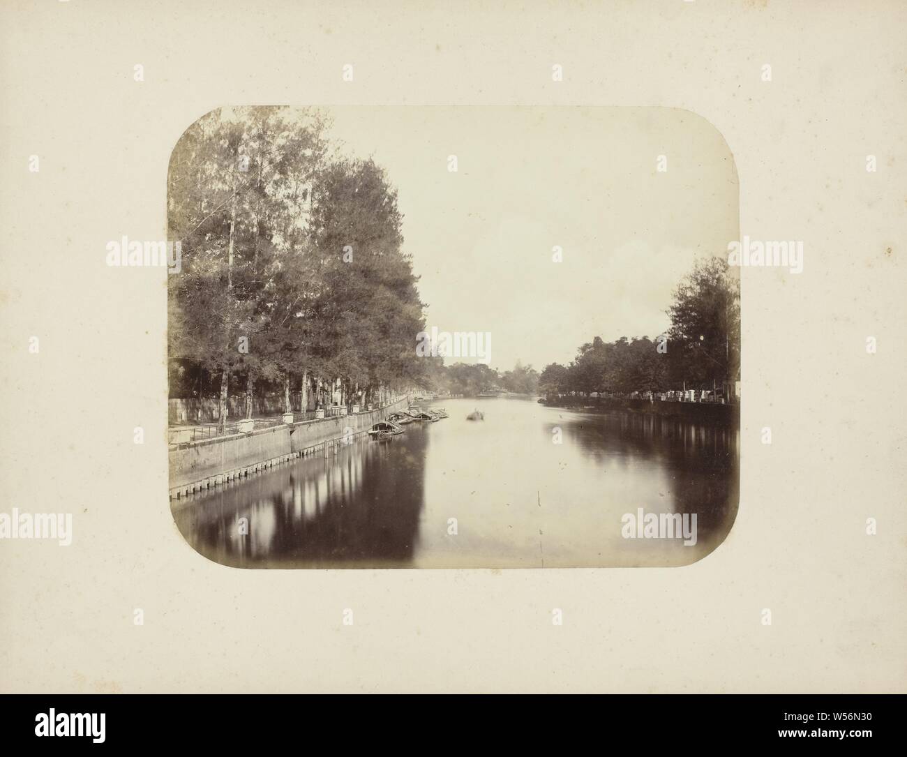 La Kali Mas, il Kali Mas in Surabaya con collegamenti con un alto muro di banchina e alberi. Un certo numero di prahoes vengono ormeggiate nel fiume. Le ombre degli alberi sono in acqua su entrambi i lati. Parte dell'album di foto dalla Soerabayasche associazione dei fabbricanti di zucchero offerto di Frederik Beyerinck residente a Surabaya., Surabaya, Herman Salzwedel, 1876 - 1884, carta fotografica, albume stampa, h 22.2 cm × W 27,6 cm Foto Stock