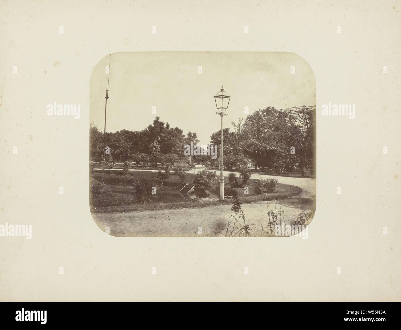 Il parco della città di Surabaya, il parco della città di Surabaya con un lampione nel centro e un grande albero sulla sinistra. Ci sono molte sedie lungo la passerella. Nel mezzo di un laghetto con una scala di legno. Parte dell'album di foto dalla Soerabayasche associazione dei fabbricanti di zucchero offerto di Frederik Beyerinck residente a Surabaya., Surabaya, Herman Salzwedel, 1876 - 1884, carta fotografica, albume stampa, h 20 cm × W 24,5 cm Foto Stock