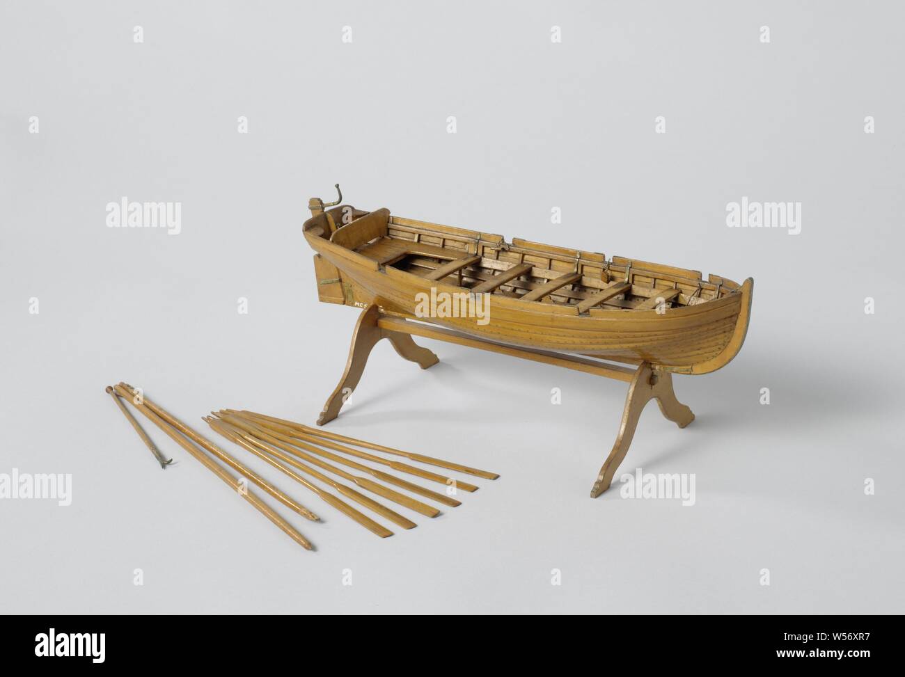 Modello di una barca Jolly, modello reticolare con tondo in legno su un cavalletto. Over-caviglia giuntata sloop, spiked traliccio rotondo con quasi piatta a strapiombo e specchio piatto, un piazzale antistante, cinque offusca e rotaie e di una cabina aperta con profondità laterale e di un consiglio di amministrazione. La prua è copiato. Facile mescolare il timone in ottone è piegato verso l'alto. Il legname è costituito da un montante di sollevamento con il braccio. Sei remi, Rijkswerf Rotterdam Rotterdam, c. 1819, di legno (materiale vegetale), ottone (lega), h 31.4 cm (truccate) × l 29,4 cm × w 9,5 cm Foto Stock