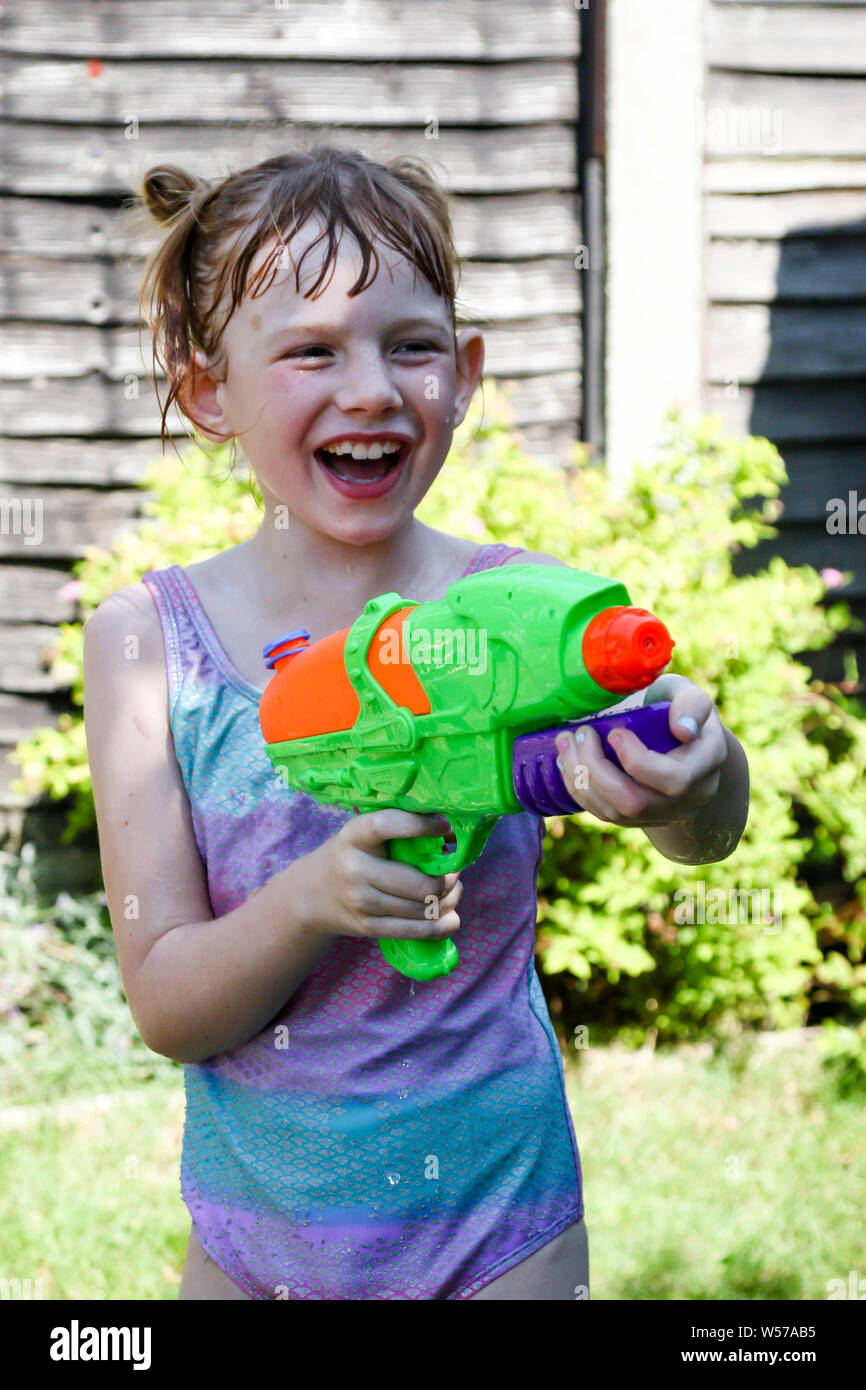 Preteen ragazza caucasica giocando wth una pistola ad acqua in una calda giornata estiva Foto Stock