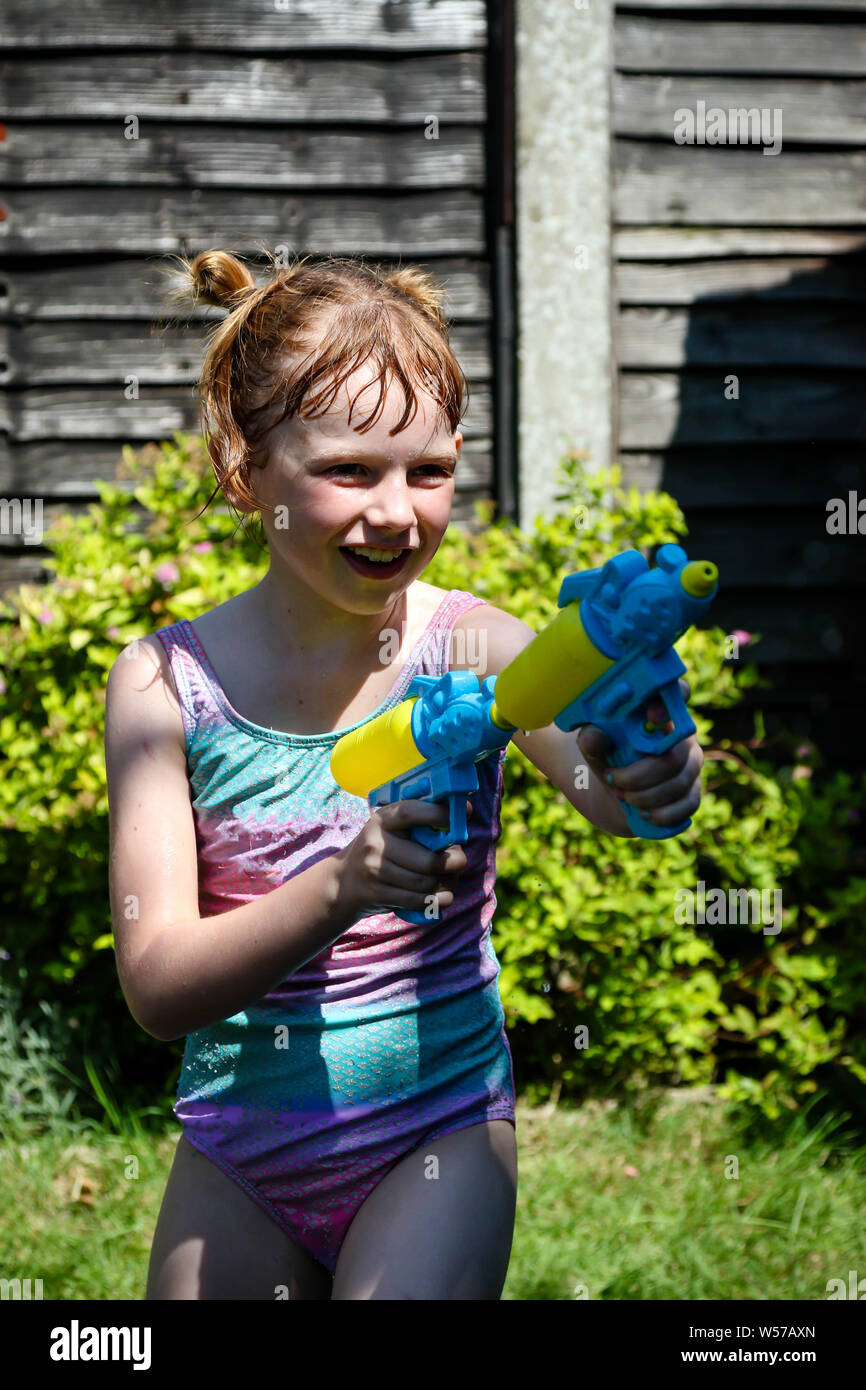 Preteen ragazza caucasica giocando wth pistole di acqua in una calda giornata estiva Foto Stock