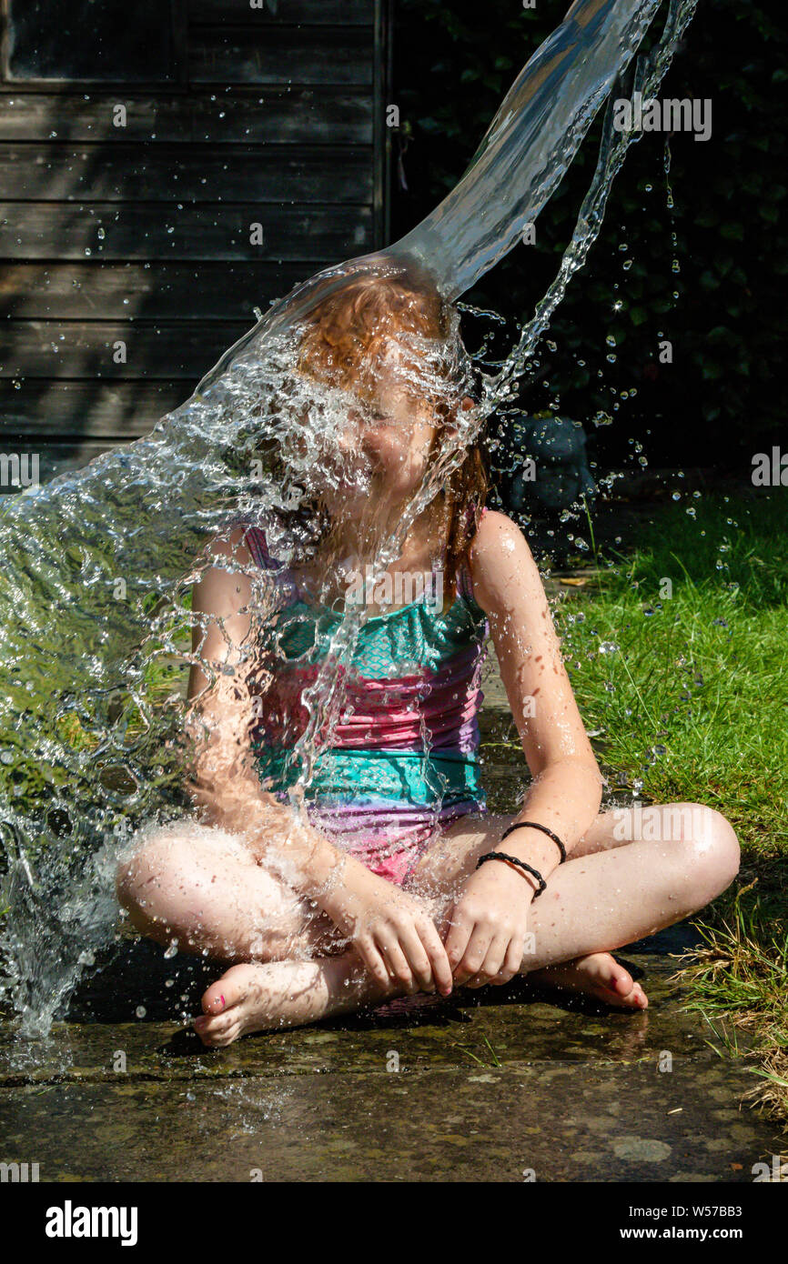 Preteen ragazza caucasica che vengono spruzzati con acqua Foto Stock
