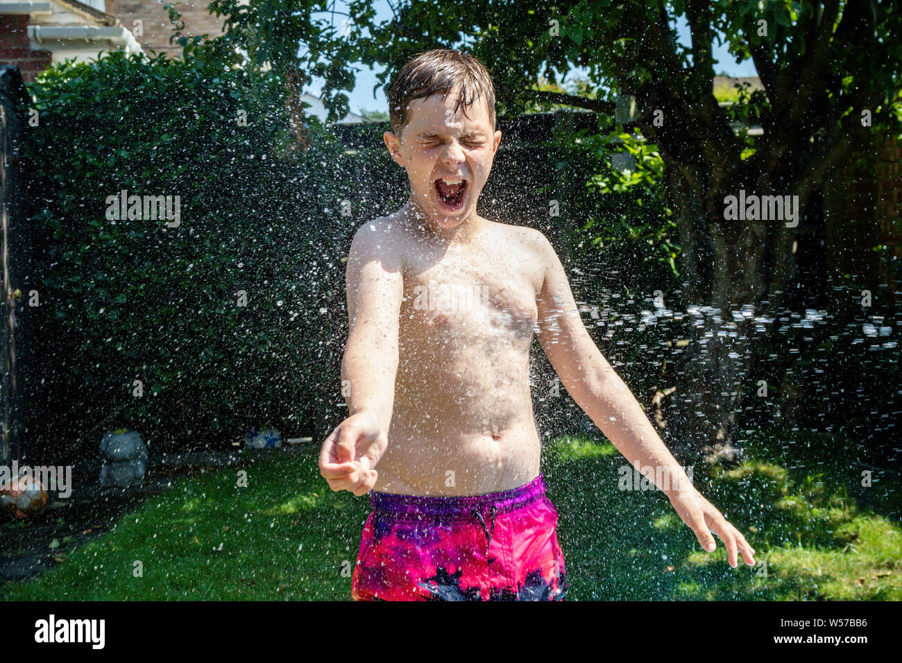 Preteen caucasian boy che vengono spruzzati con acqua Foto Stock