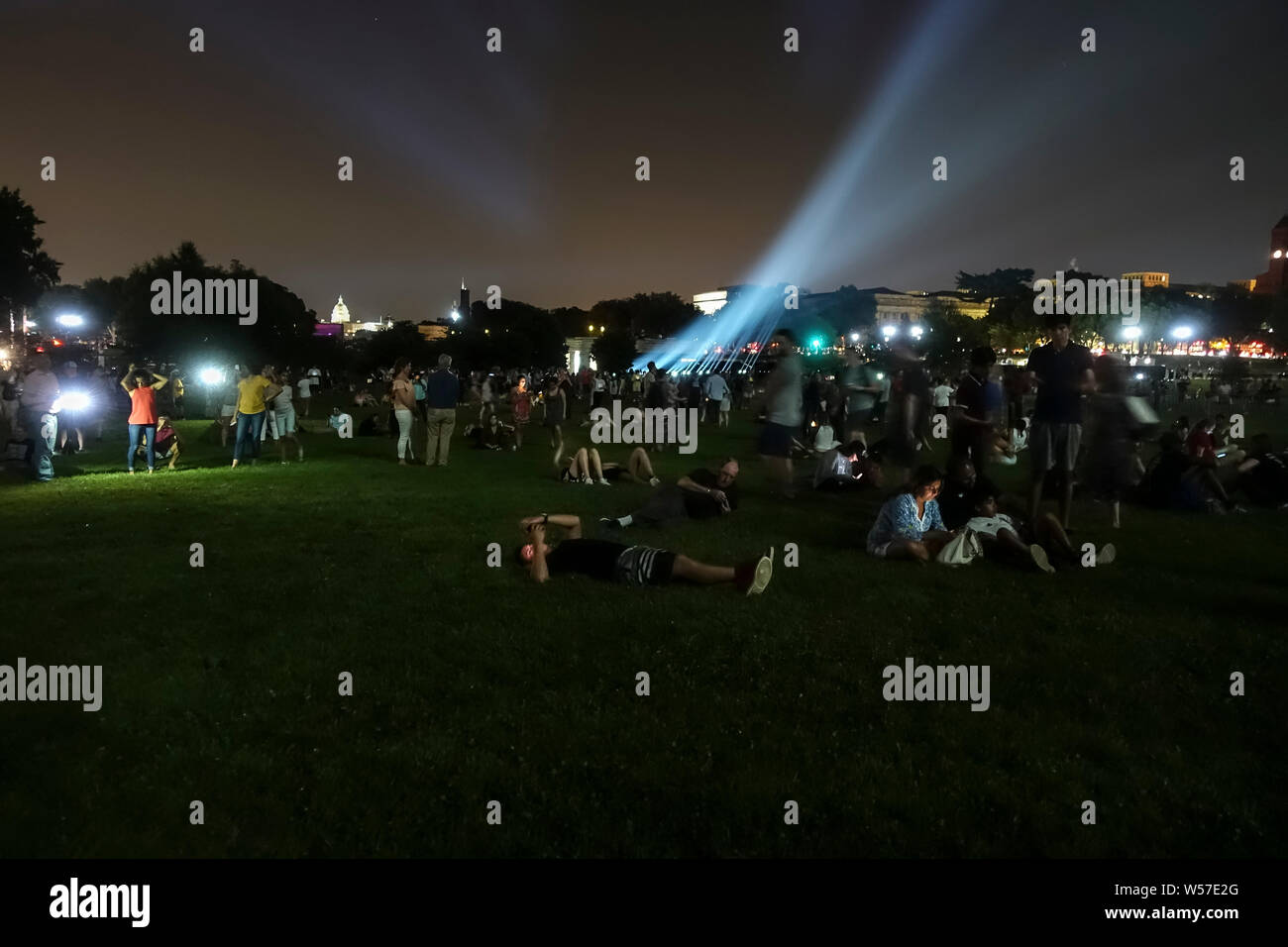 Washington, DC - Luglio 18, 2019. Per celebrare il cinquantesimo anniversario del primo allunaggio, i turisti e la gente del posto lo sguardo fino ad una immagine di un Saturn V rocket che viene proiettata sul Monumento di Washington, parte di un corso di cinque giorni per commemorare l'Apollo 11 sbarco sulla luna nel 1969. Foto Stock